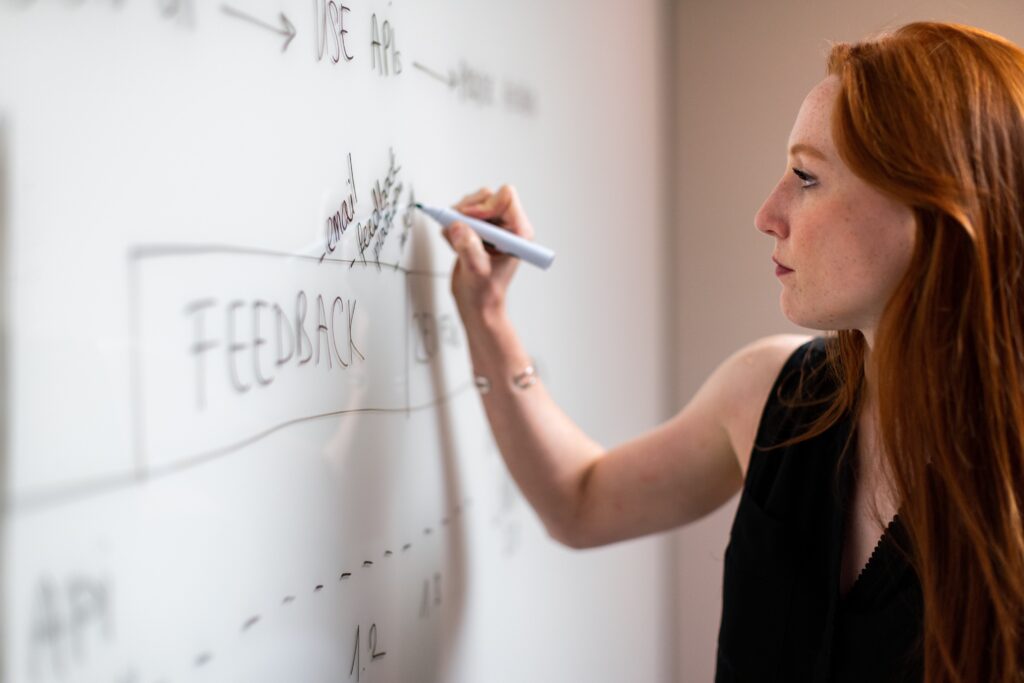 Roodharige vrouw schrijft met whiteboard maker feedback op een whiteboard