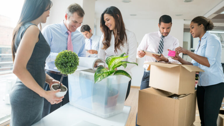 Latin American group of business people moving to a new office and packing in cardboard boxes